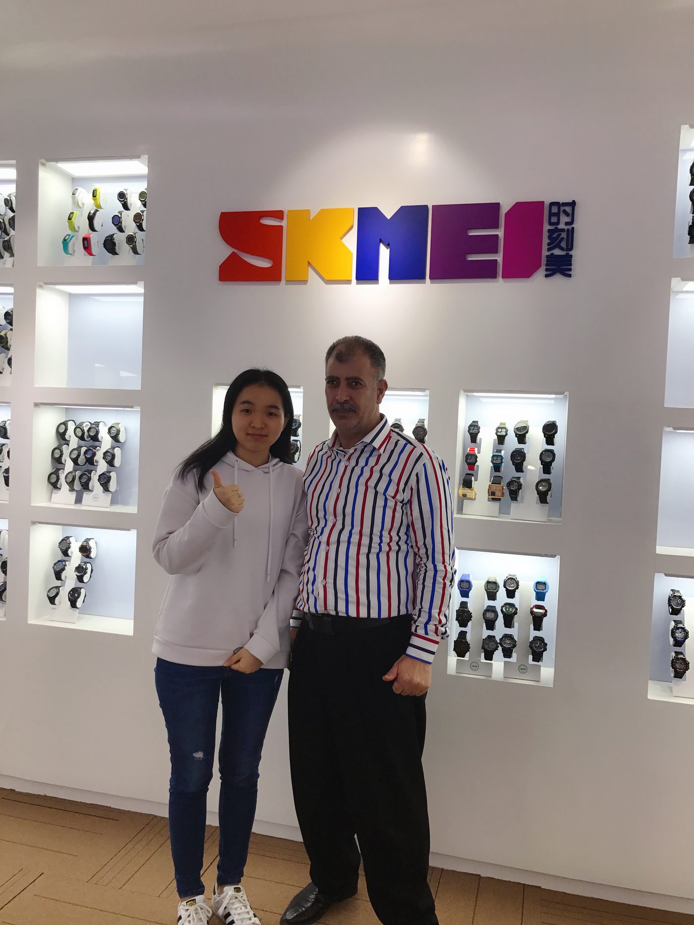 Overseas customer with a SKMEI representative in front of the showroom sample wall, April 2019