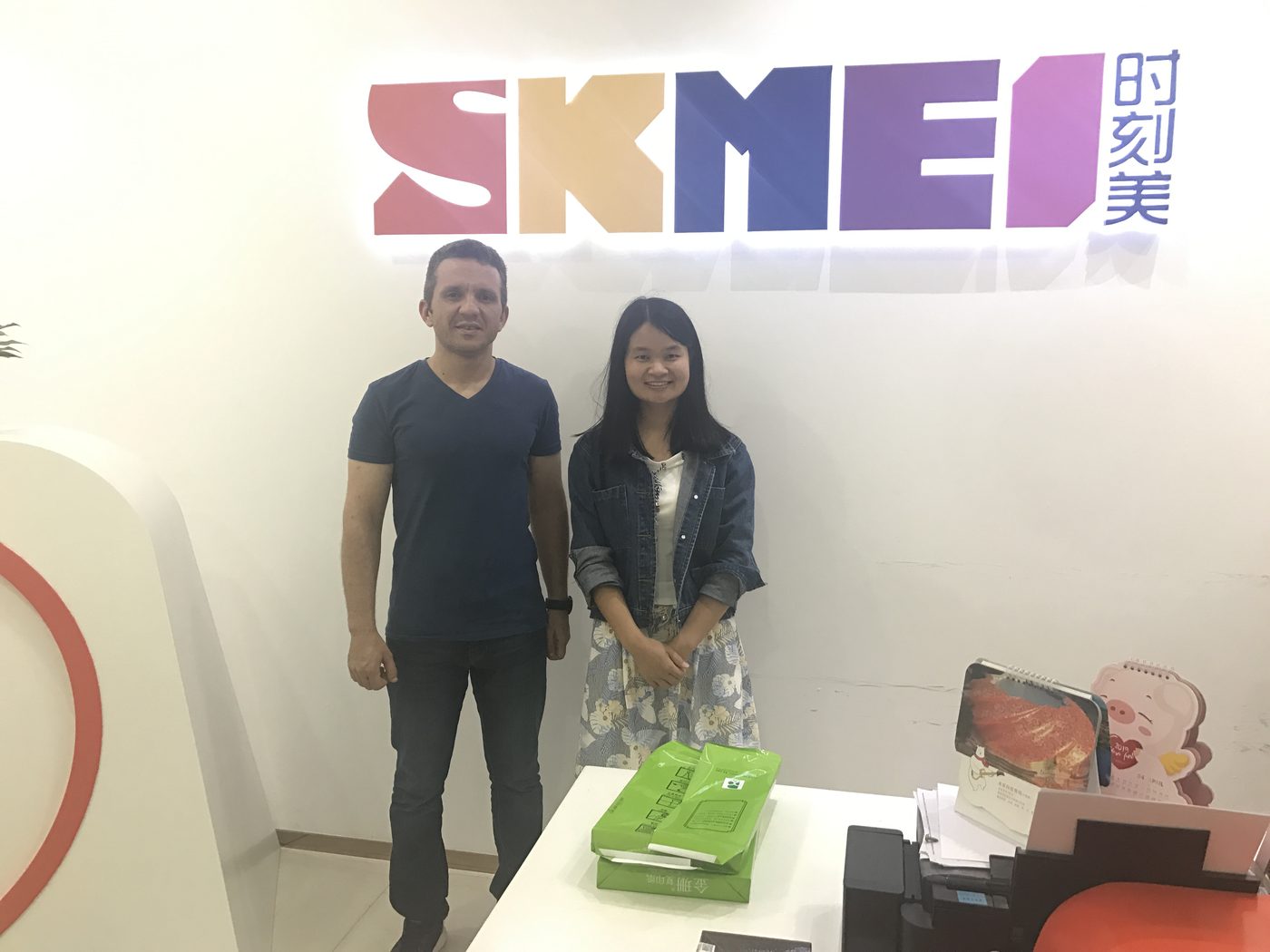 Overseas customer with a SKMEI representative at the showroom logo wall, April 2019