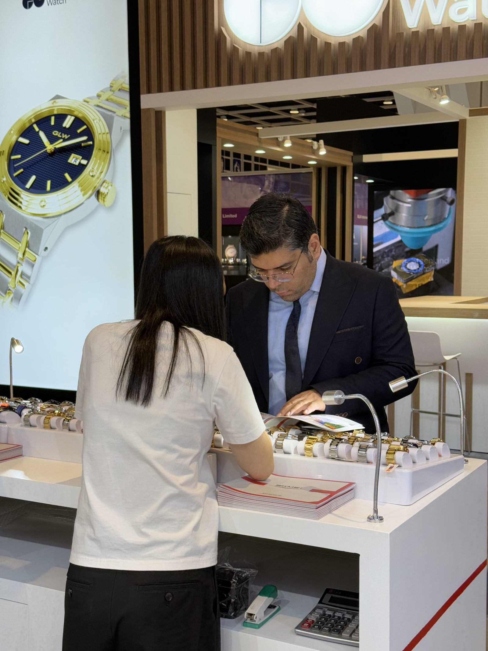An overseas buyer reviewing the SKMEI catalogue with a sales representative at the 2025 Hong Kong booth